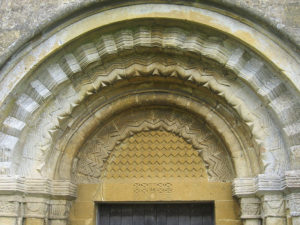 A Norman arch with zig-zag mouldings above the church doorway at Guiting Power, Gloucestershire